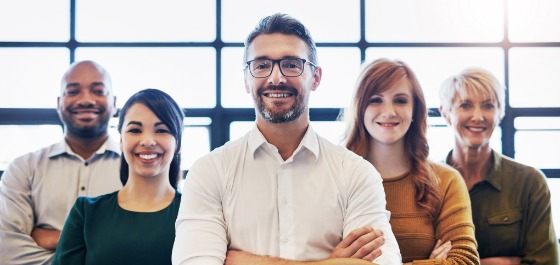 Weiterbildung & Deutsch verbessern Kachel: Team von Kollegen, die mit verschränkten Armen in einem modernen Büro stehen.